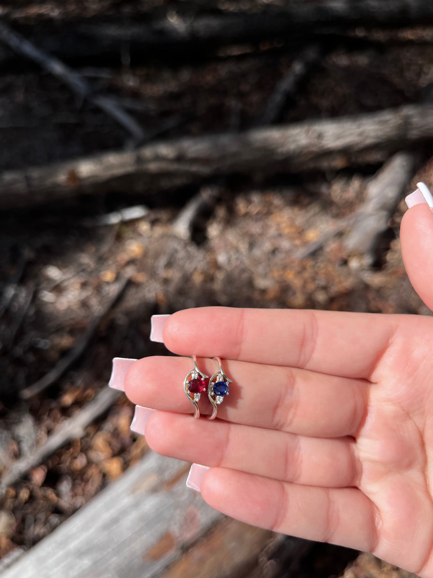A hand holding a small, multicolored ring with a unique design, possibly made of crystal, set in a metal setting.