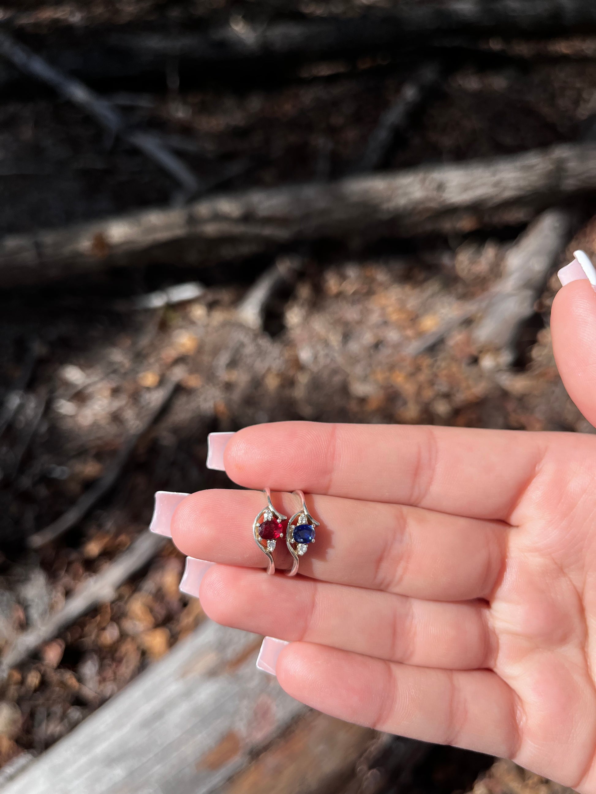 A hand holding a small, multicolored ring with a unique design, possibly made of crystal, set in a metal setting.